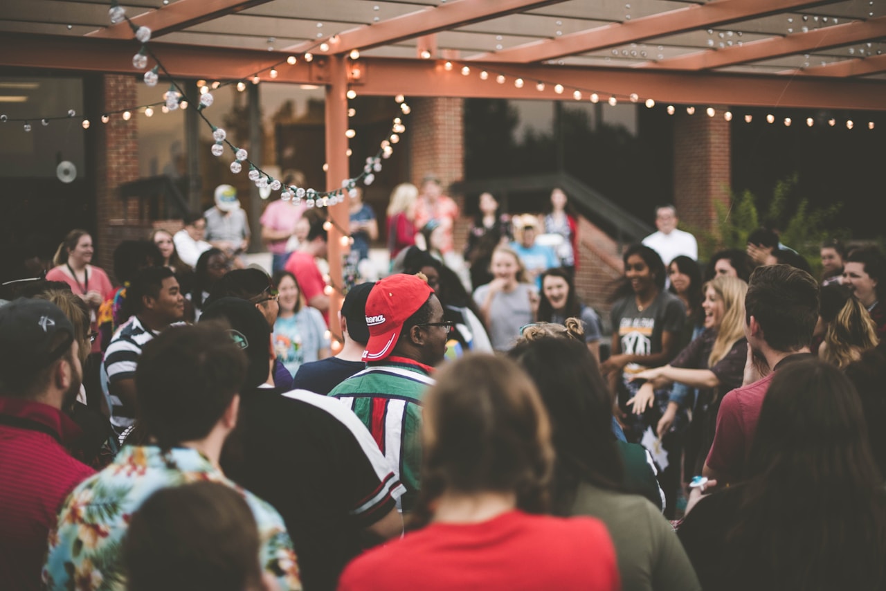 A diverse community gathered together at an outdoor evening event.